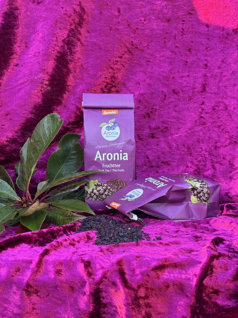 Pose med aronia frugt-te og løse tørrede bær foran posen.